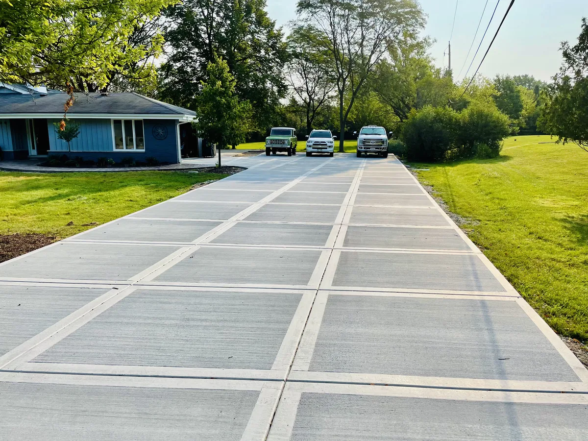 Wide concrete driveway with evenly spaced control joints running up to a single story home