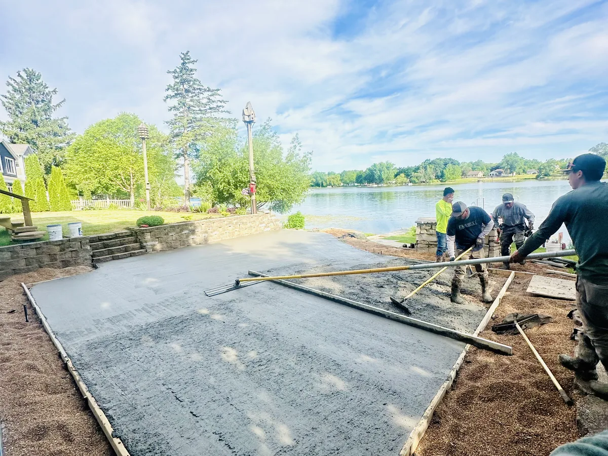 Crew screeding wet concrete flat with a straightedge on a waterfront property