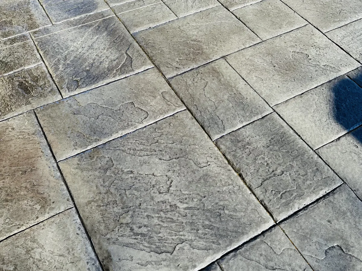Close view of gray stamped concrete pressed in an ashlar slate pattern with tooled joint lines